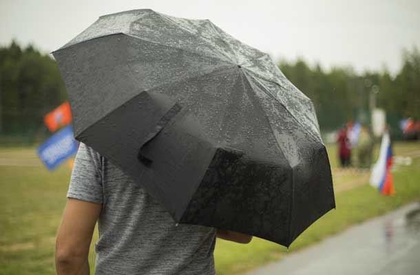 Man under umbrella standing in the rain at an event